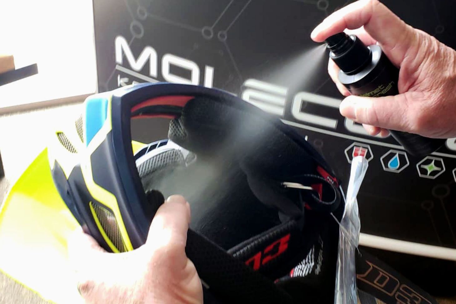 Spraying Molecule Helmet Refresh into helmet interior